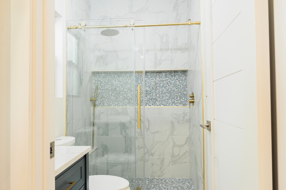 Stylish ADU bathroom with marble tile shower, mosaic accent wall, and sliding glass door