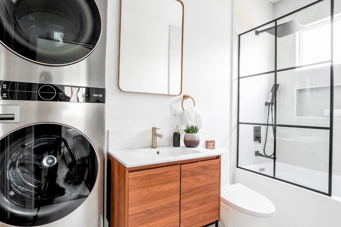 Contemporary ADU bathroom with floating wood vanity, black framed mirror, and tub-shower combo