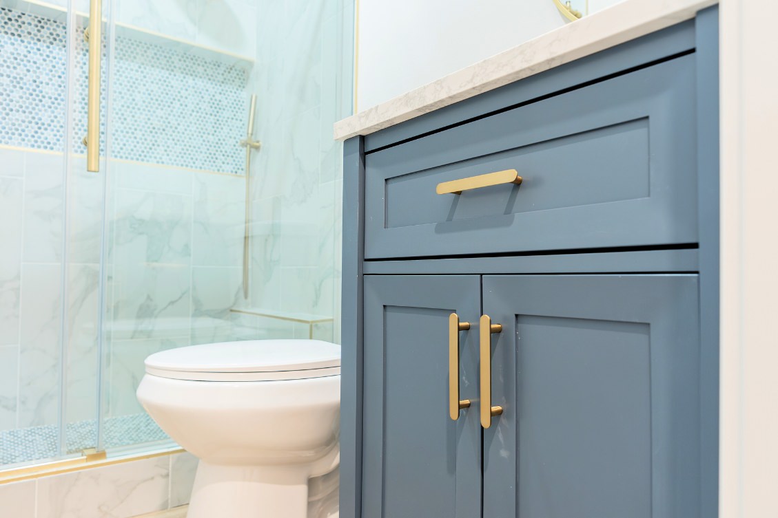 Elegant ADU bathroom with blue vanity, marble countertop, and gold hardware