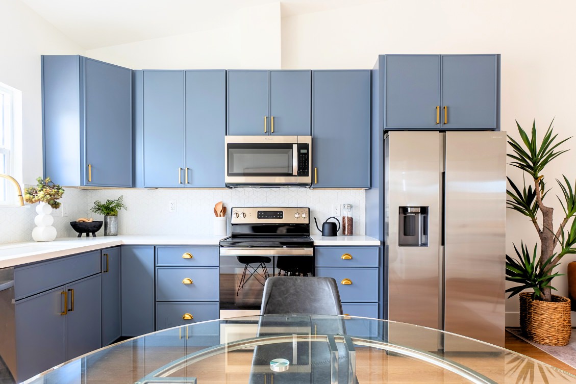 Contemporary ADU kitchen with blue cabinetry, gold handles, and stainless steel appliances