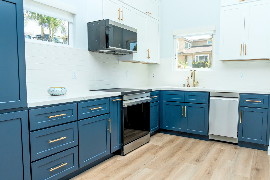 Modern ADU kitchen with navy and white cabinetry, gold handles, and stainless steel range