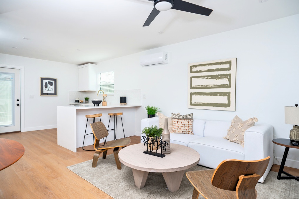 Contemporary ADU living space with white sofa, modern art, and open kitchen island