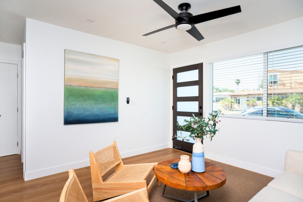 Minimalist ADU living area with natural wood coffee table, modern art, and black front door