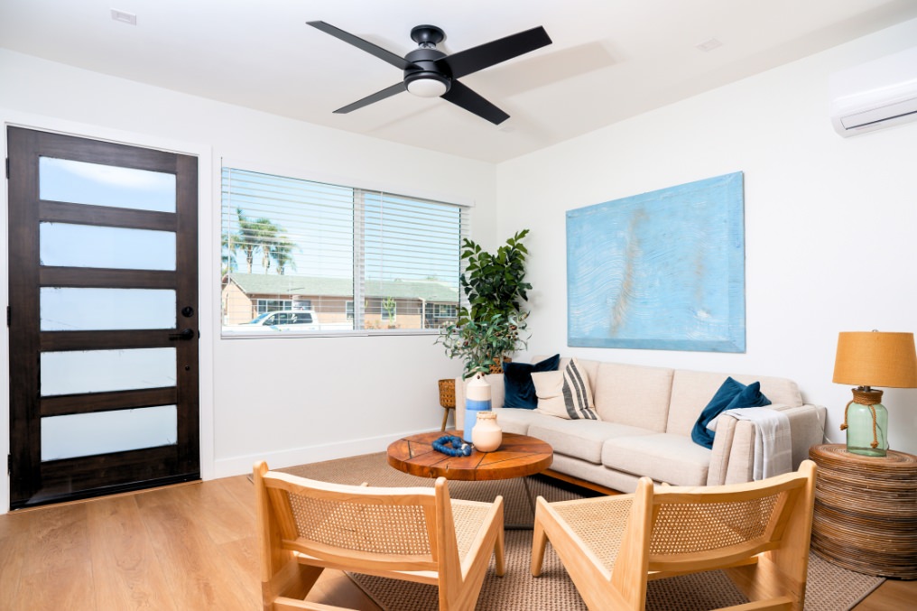 Contemporary ADU living room with neutral sofa, blue accent art, and mid-century chairs