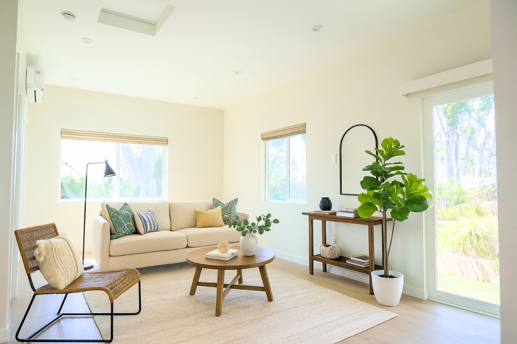 Modern ADU living room with beige sofa, green accent pillows, and potted plant décor