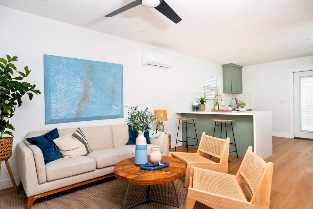 Open-concept ADU living room with sofa, blue wall art, and kitchen island seating