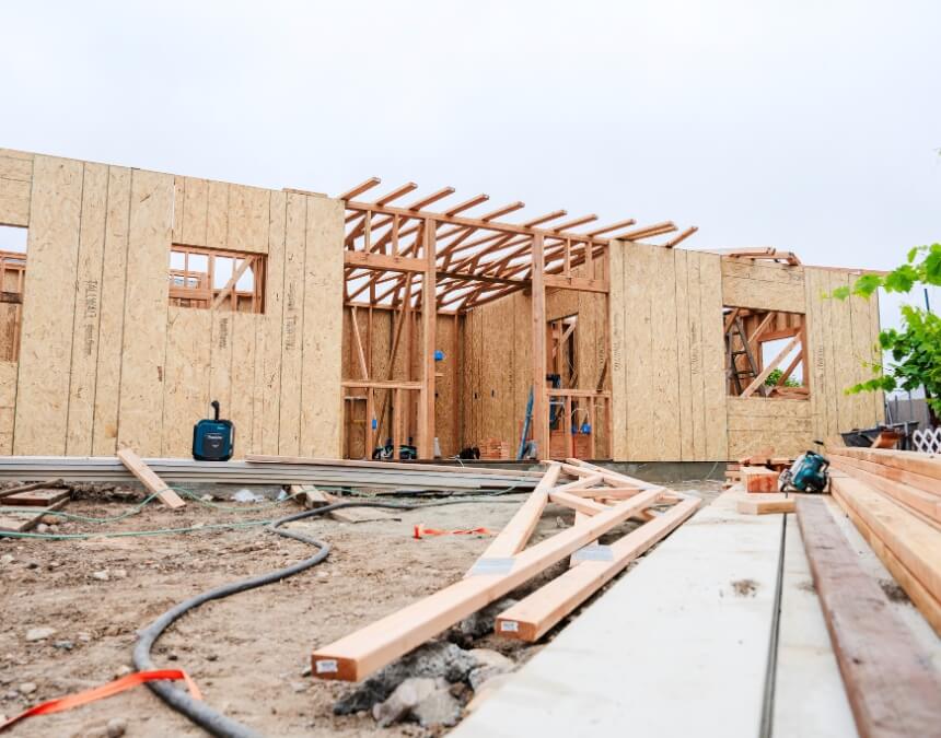 A wooden-framed ADU structure under construction surrounded by trees — The ADU Construction Process Overview visual.