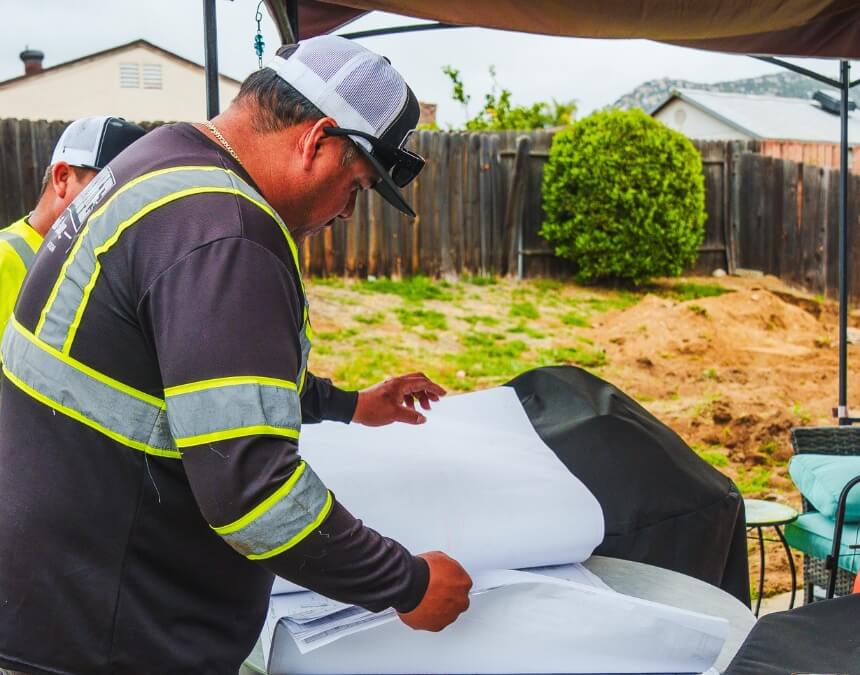 Costs and Compliance image of an ADU professional reviewing plans on site, highlighting budgeting and permit review for retaining walls.