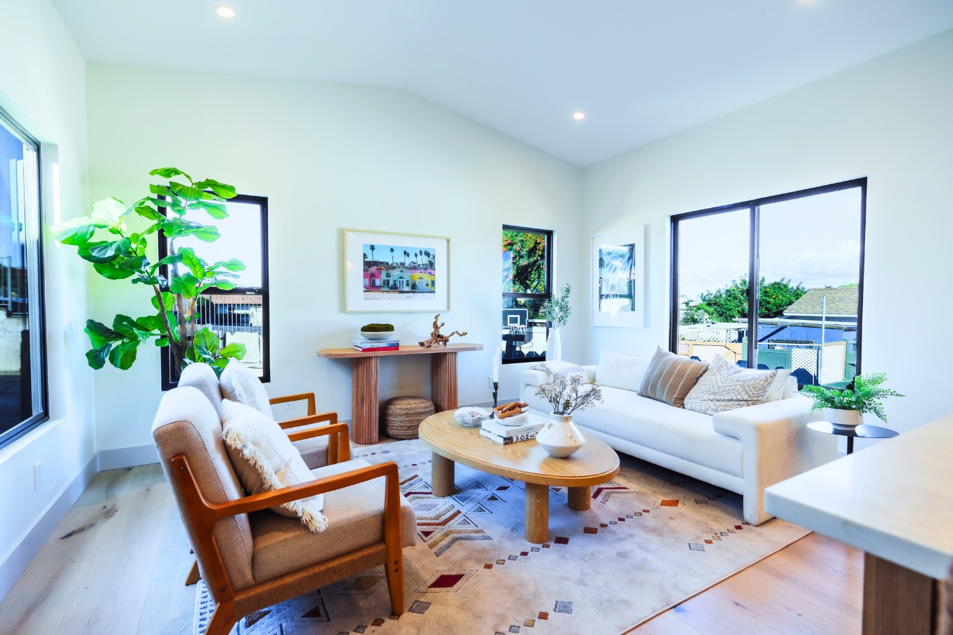 Bright, airy living room inside the Linda Vista Detached ADU with large windows, modern furnishings, indoor plants, and natural light.