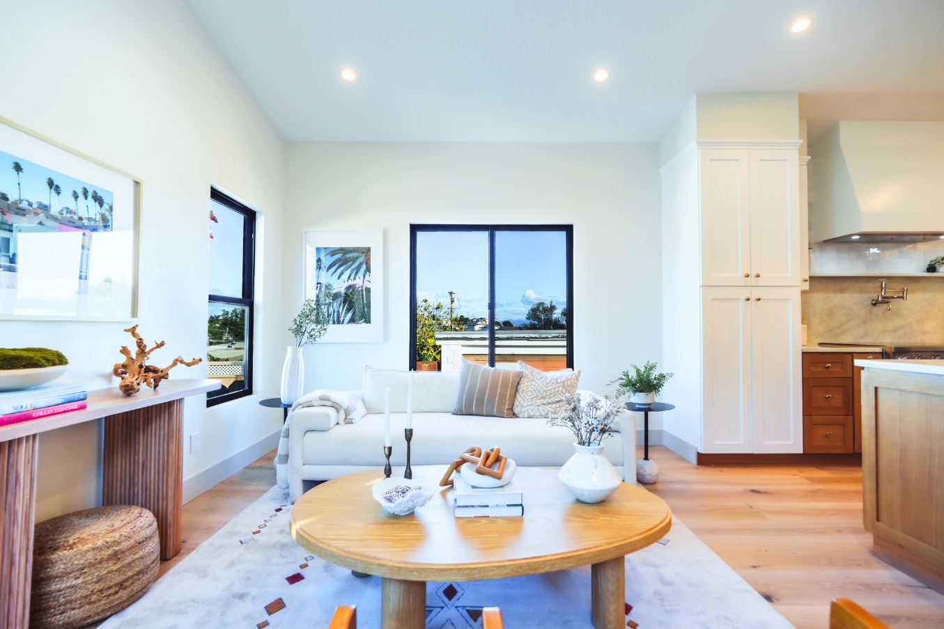 Central living area of the Linda Vista Detached ADU featuring a white sofa, curated decor, framed artwork, and expansive windows.