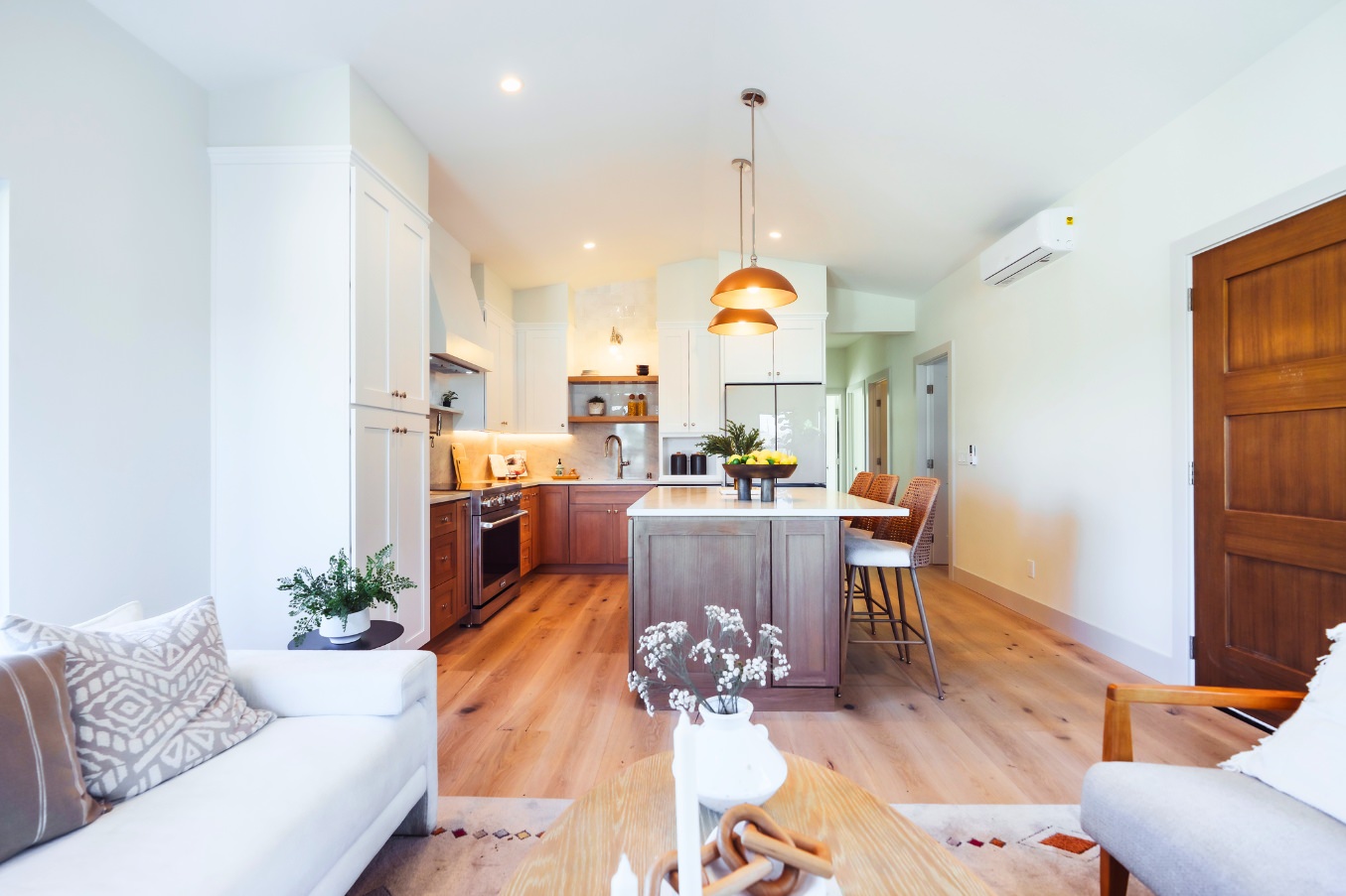 Open-concept interior of the Linda Vista Detached ADU showcasing a warm wood kitchen island, pendant lighting, white cabinetry, and a connected living space.