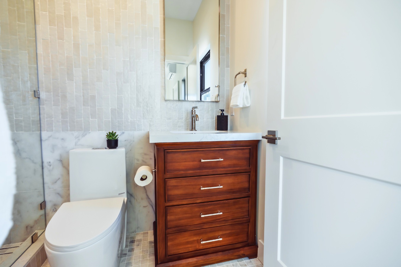 Secondary bathroom in the Linda Vista Detached ADU featuring a wood vanity, marble accents, vertical textured wall tile, and modern fixtures.