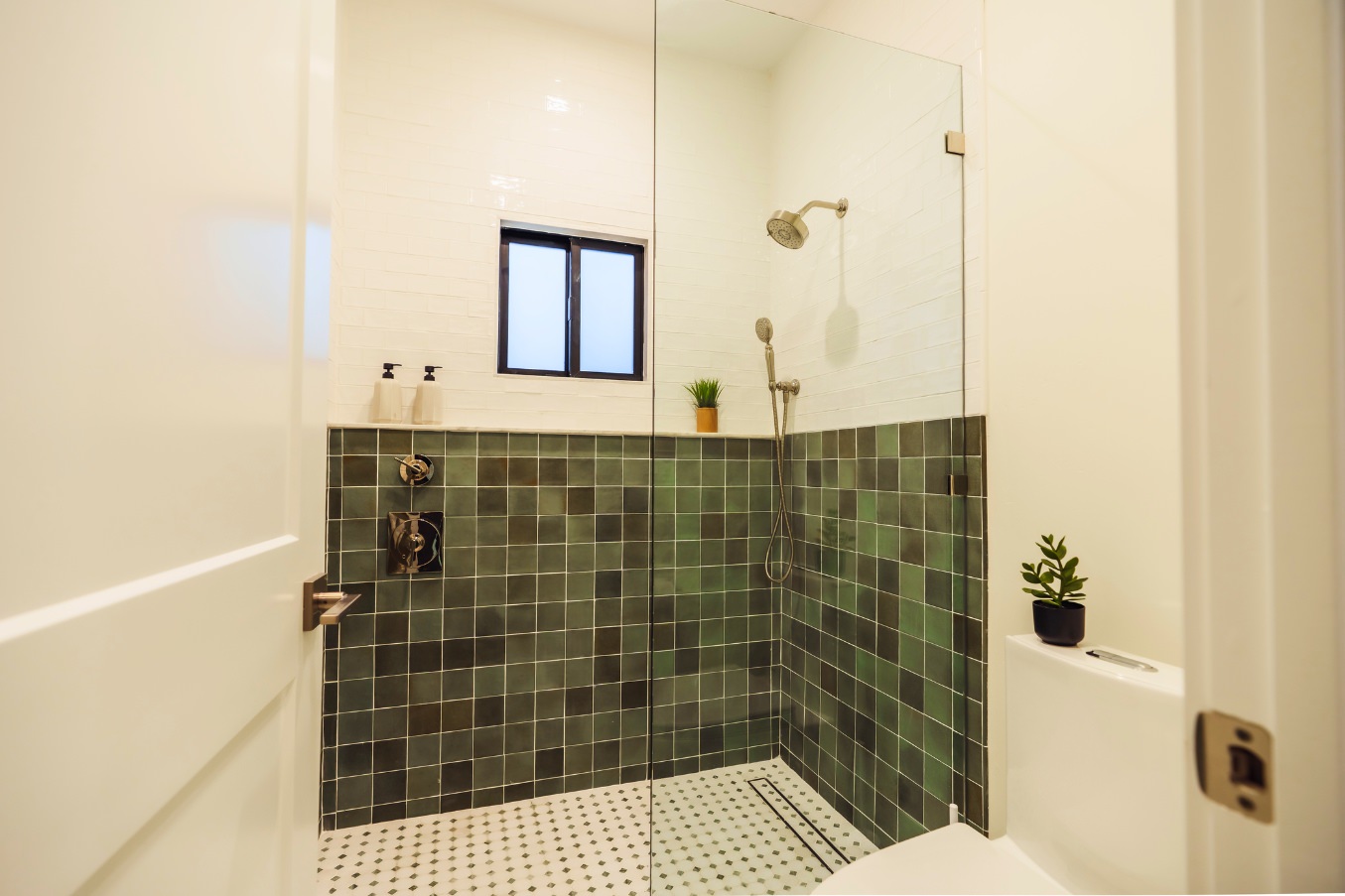 Walk-in shower inside the Linda Vista Detached ADU featuring green square tile, a glass enclosure, a rain shower head, and a frosted window.